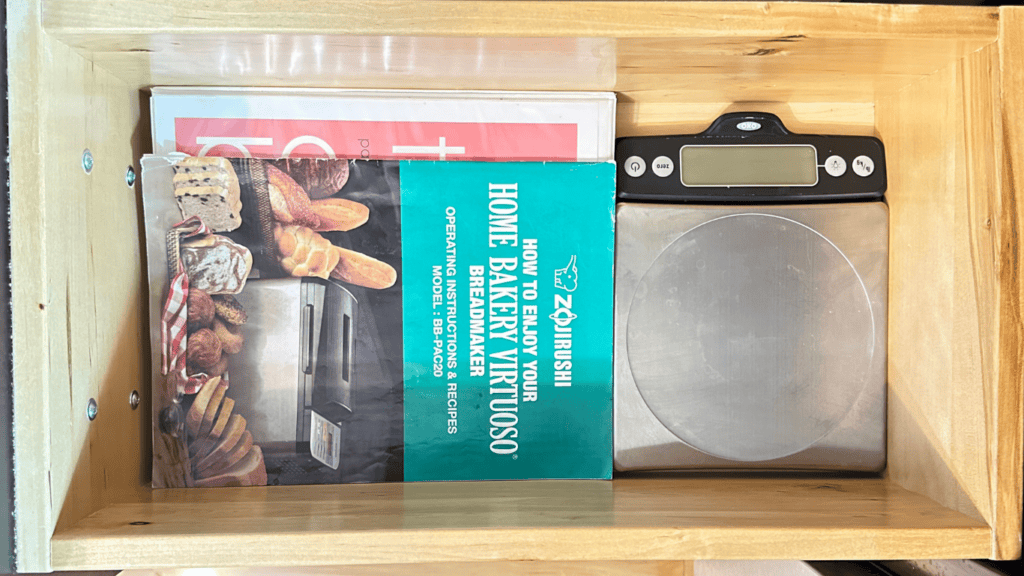 two cookbooks and a food scale in a kitchen drawer