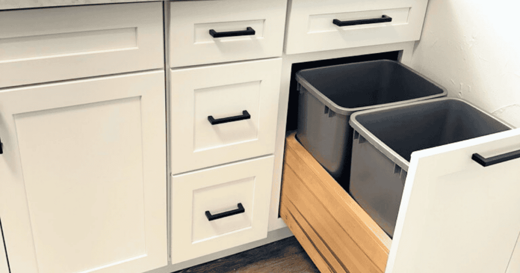 pullout garbage can in a white kitchen cabinet