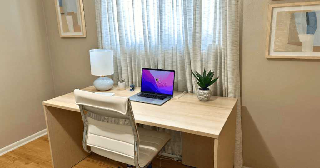 A desk with a computer, lamp, and plant on it