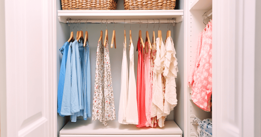 White closet with pastel colored shirts hanging up