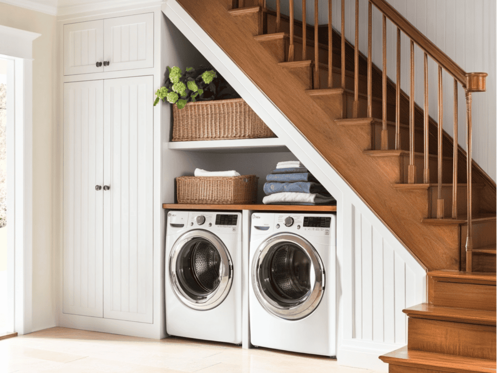 Washer and dryer under a staircase beside a storage cabinet