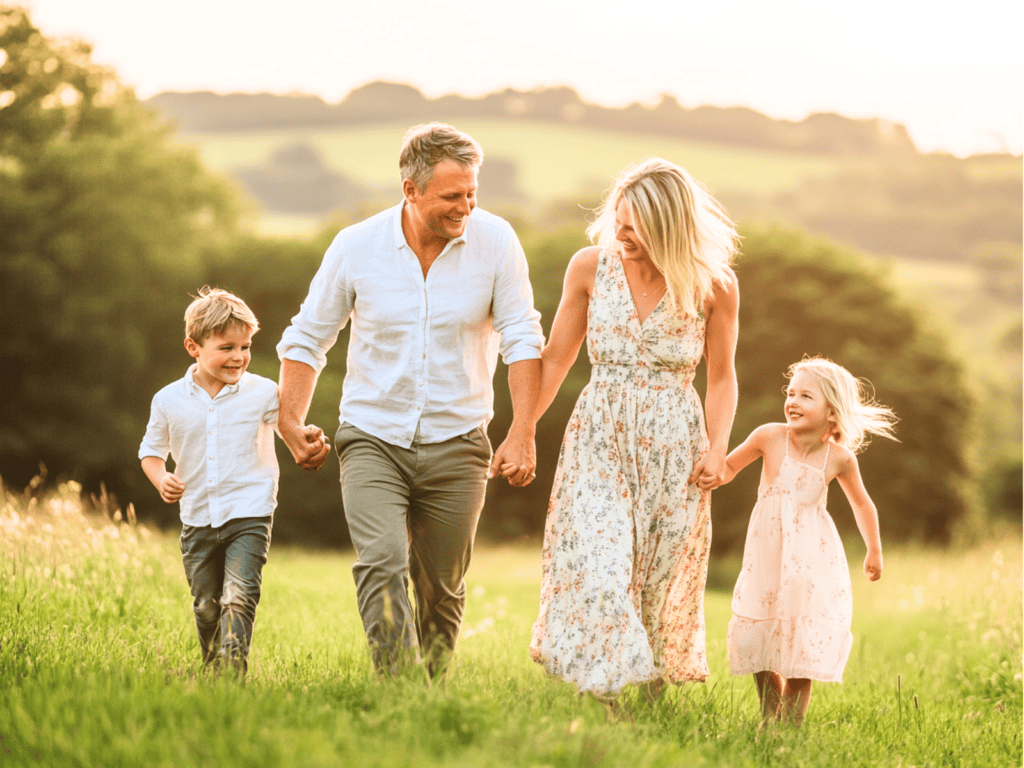 A man and woman and two children holding hands and smiling