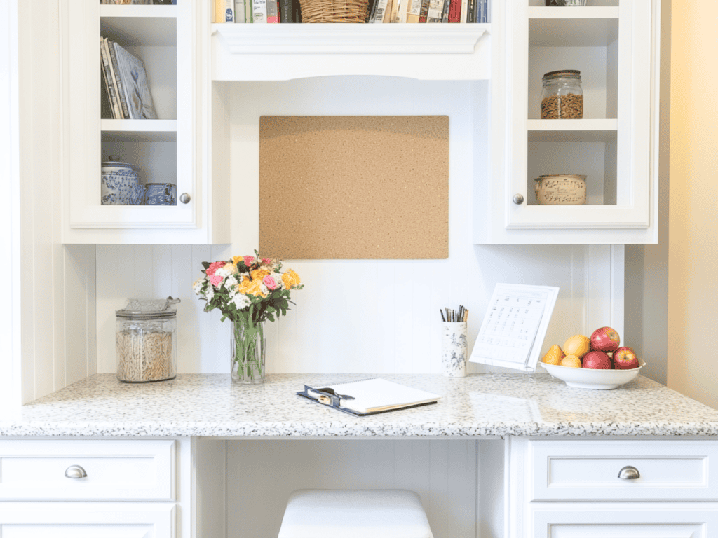 An organized desk in a kitchen nook with shelves and a corkboard