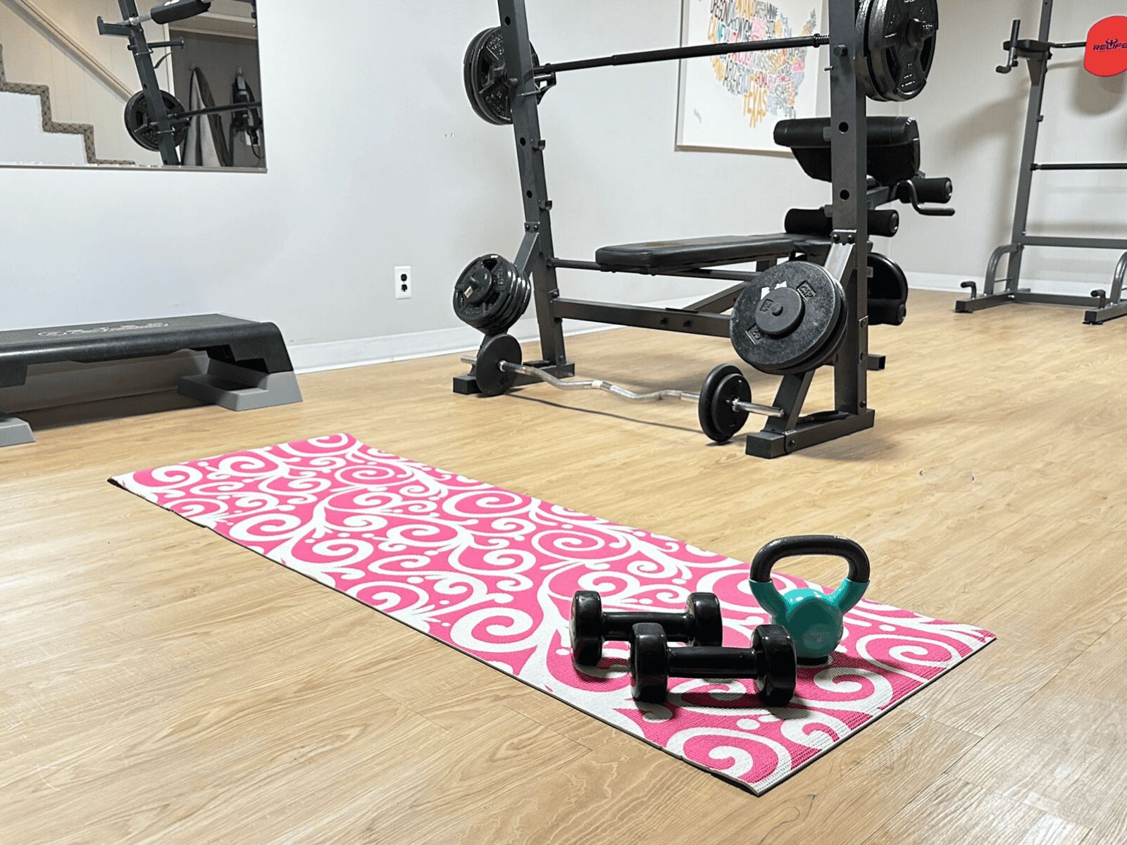 My pink and white yoga matt with dumbbells in my home gym