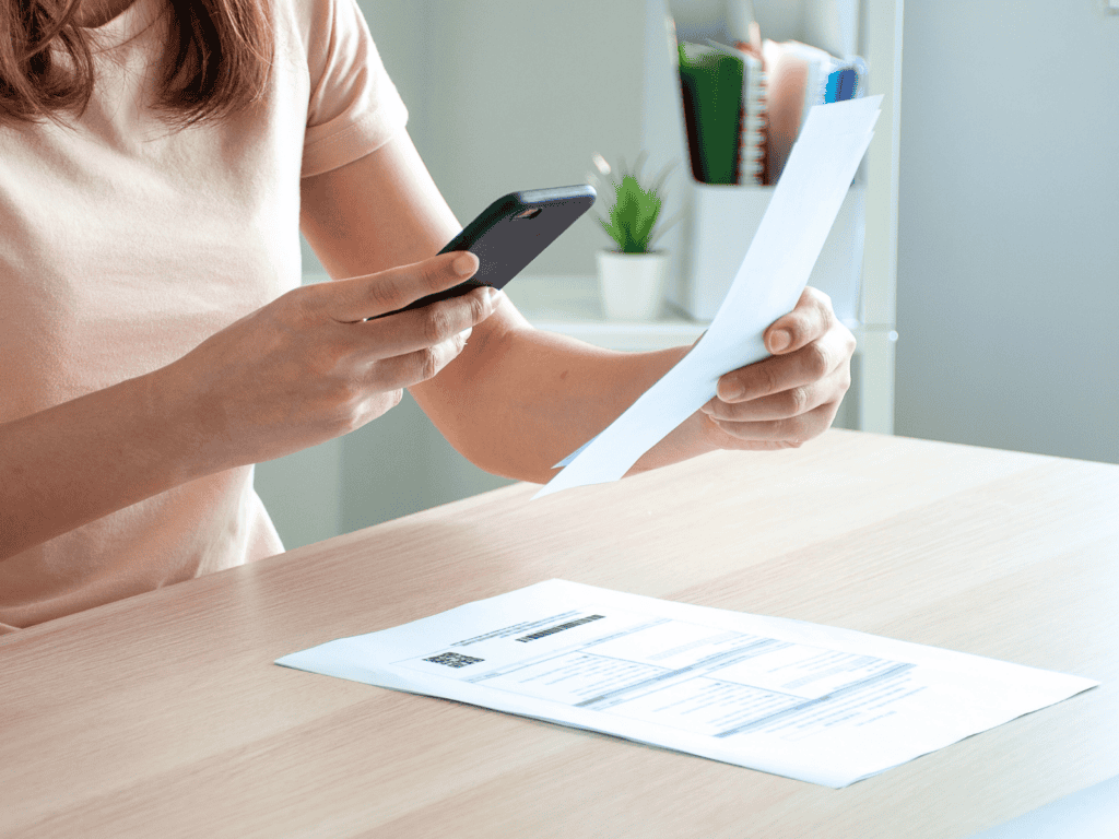 A woman using her phone to scan a child's school papers.