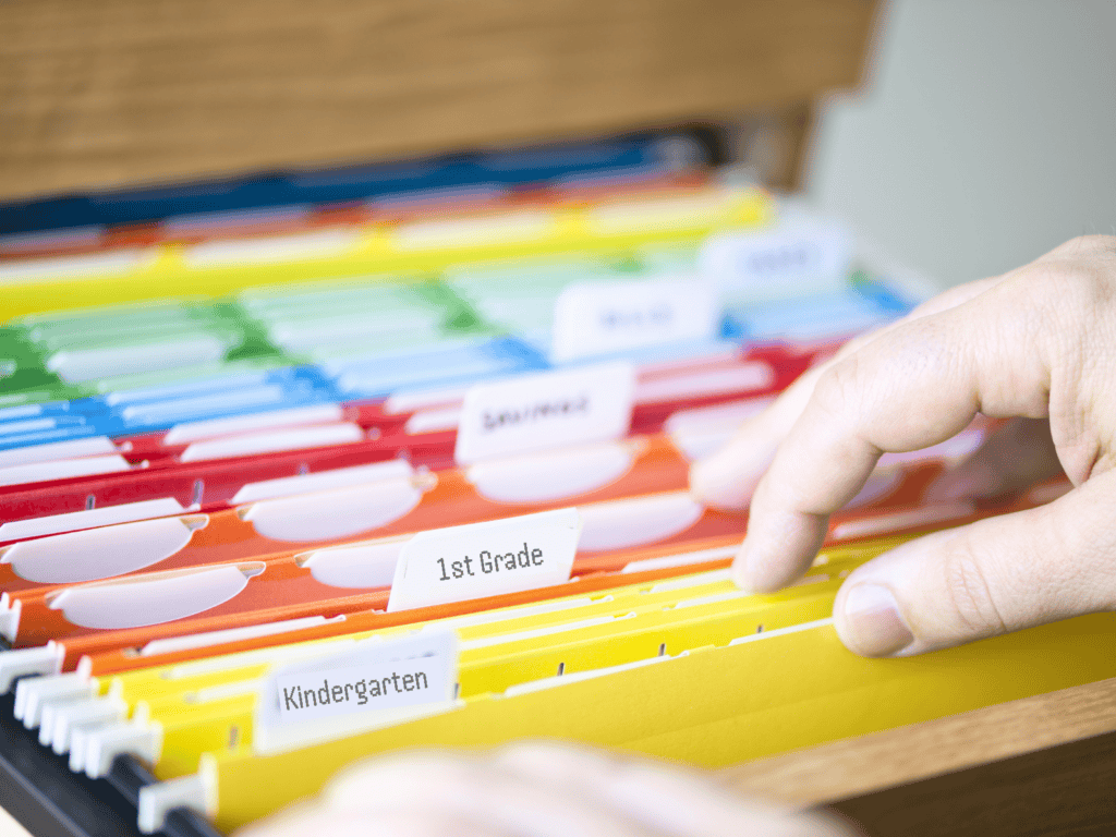 Multi-colored hanging files labeled by the grade a child is in.