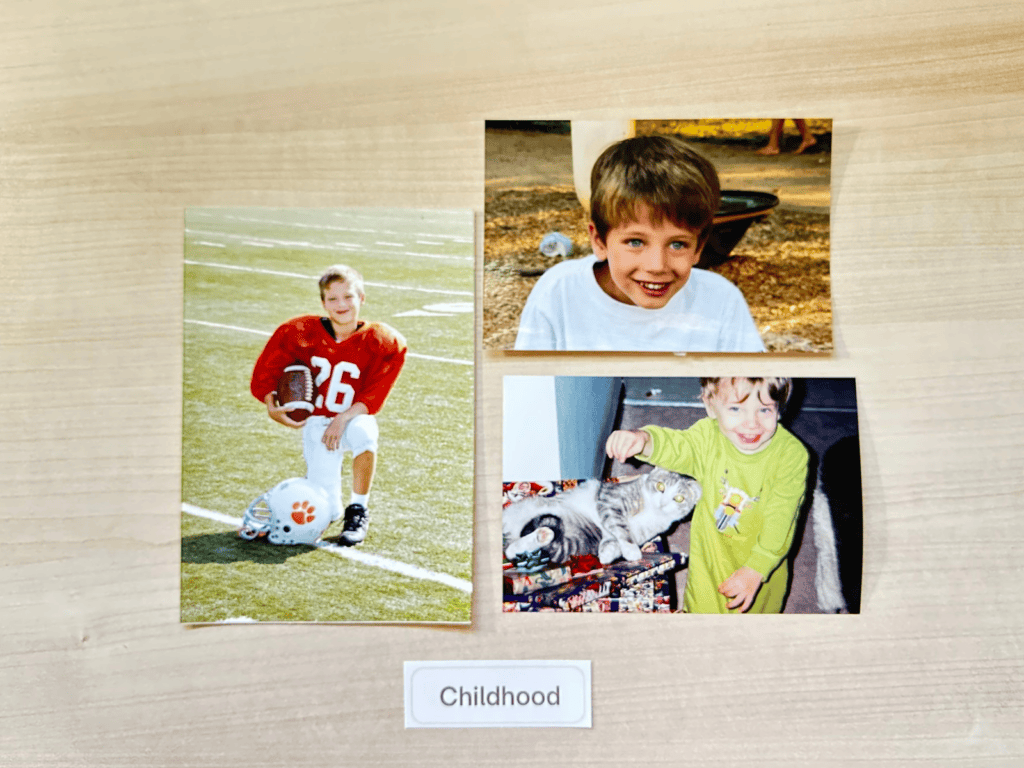 Three childhood photographs arranged on a light wood surface above a small label reading “Childhood,” showing a young boy playing football, smiling outdoors, and petting a cat.