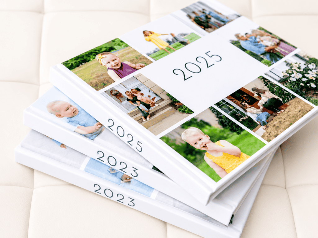 Stack of three photo yearbooks labeled 2023, 2024, and 2025, featuring collage-style covers with family and childhood photos, arranged on a soft white surface.