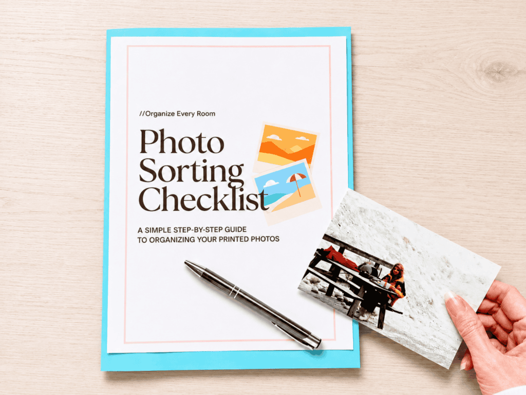 Printed photo sorting checklist on a light wood desk with a pen and a hand holding a vintage photograph, showing a simple and organized approach to sorting printed photos.